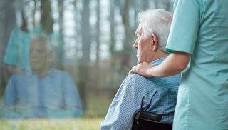 An elderly man in a wheelchair looking out a large window with a nurse